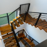 High-angle view of a contemporary wooden staircase with metal railings in a bright interior.