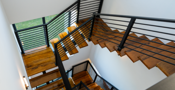 High-angle view of a contemporary wooden staircase with metal railings in a bright interior.